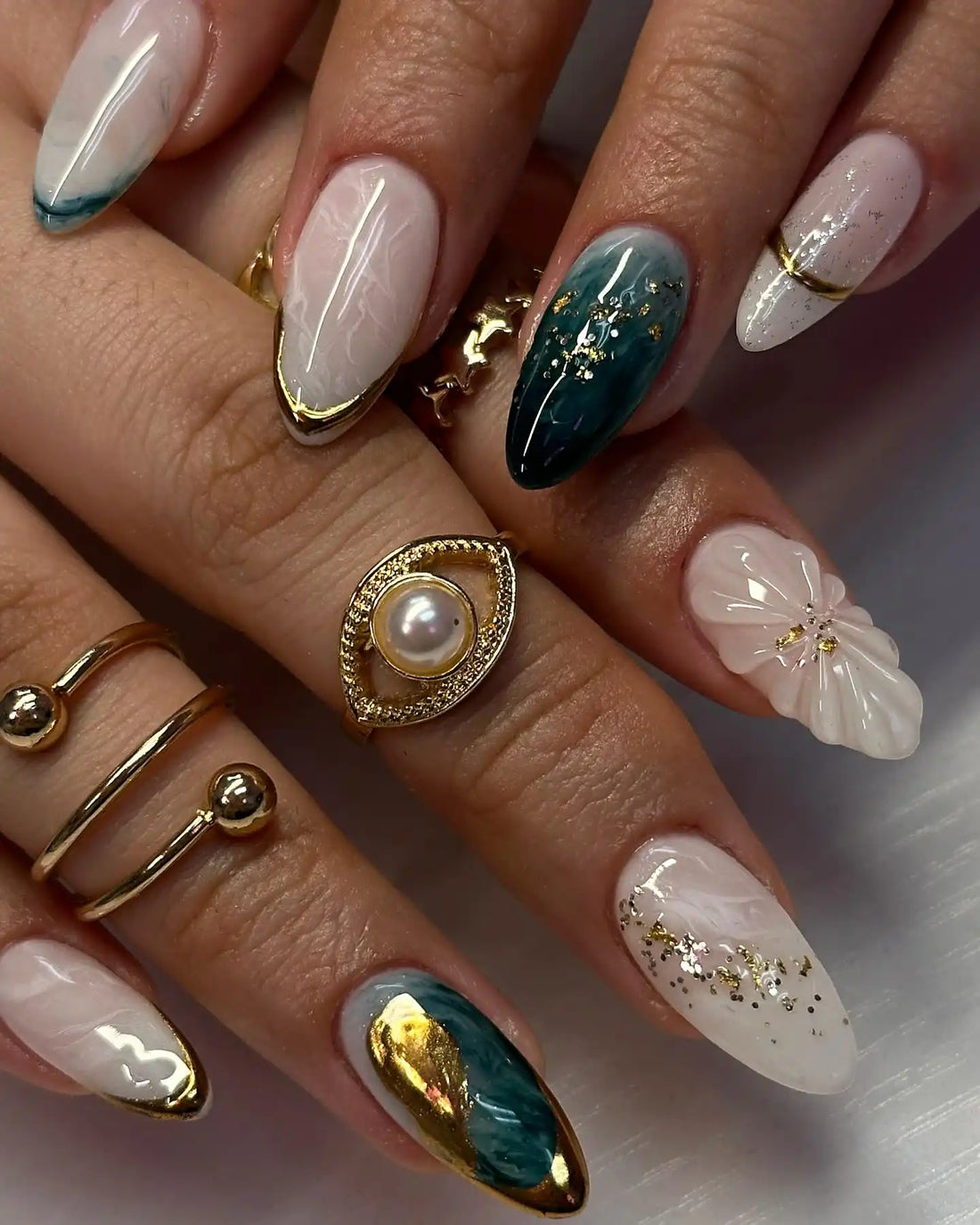 Handmade white and emerald green press-on nails with gold foil accents, floral detail, and glossy finish.