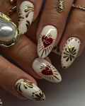 Handmade white press-on nails with gold floral accents and red heart design