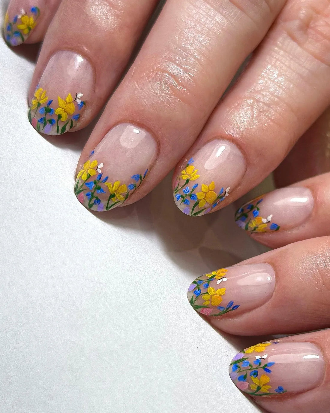 Handmade press-on nails with clear base and yellow and blue wildflower French tips