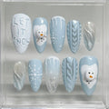 Handmade blue winter press-on nails with snowman, snowflake, icicle and sweater designs.