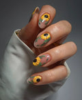 Hand with handmade press-on nails featuring yellow sunflower floral design