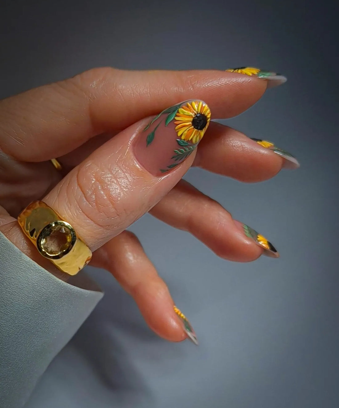 Hand with handmade yellow sunflower floral press-on nails, summer garden nail art.