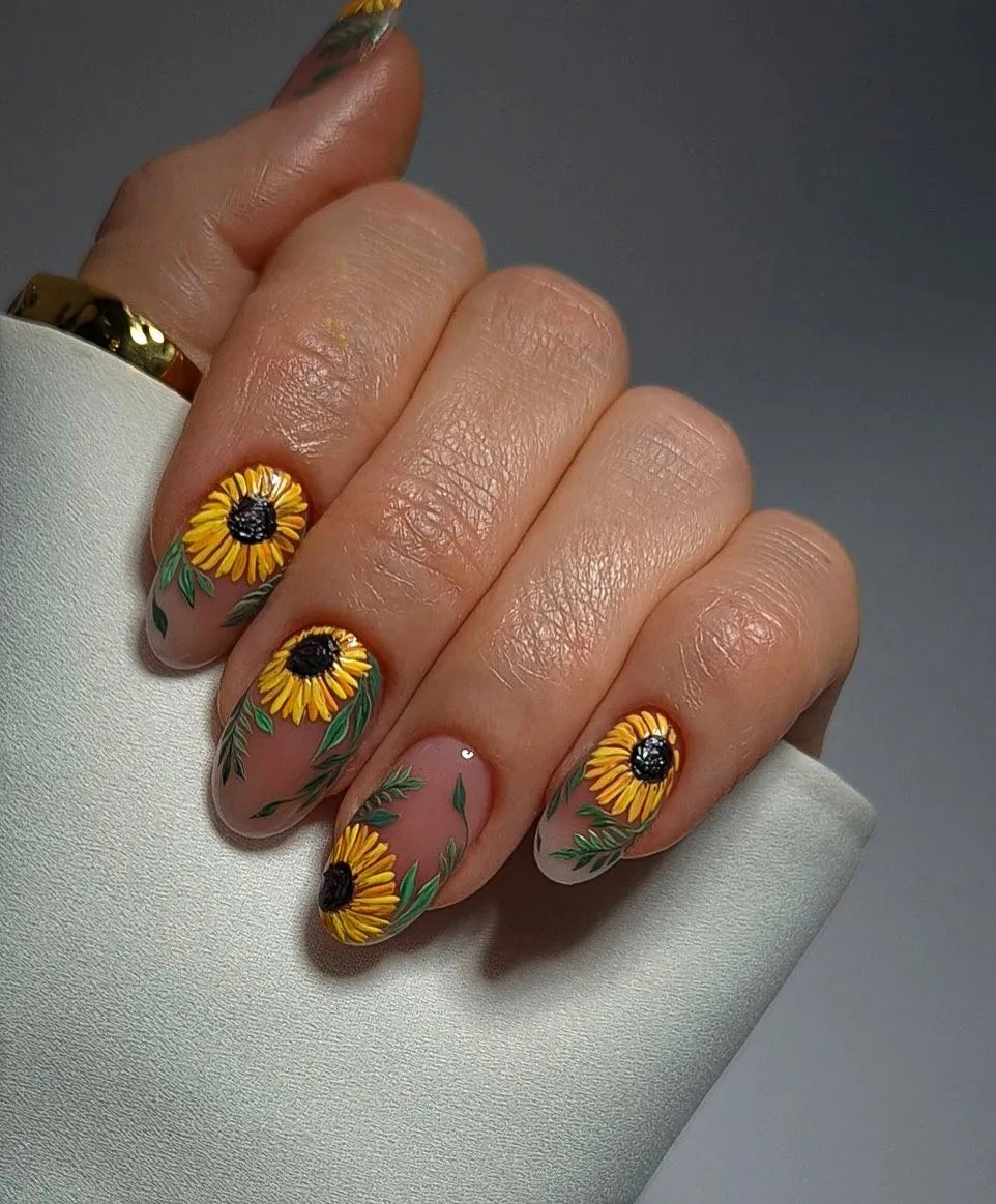 Hand with handmade yellow sunflower floral press-on nails, summer garden nail art.