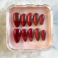 Set of shiny red cat eye glitter press-on nails in a clear pink case
