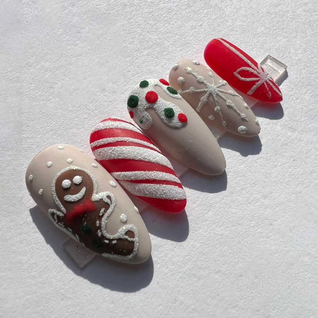 Handmade Christmas press-on nails with gingerbread man, candy cane, and festive designs.