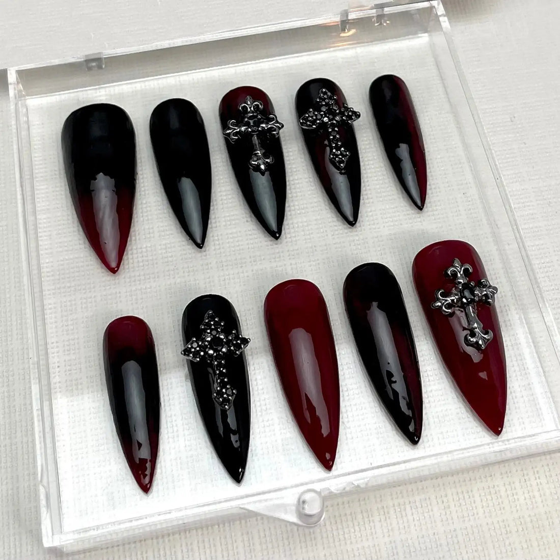 Red and black ombre stiletto Halloween press-on nails with silver cross embellishments.