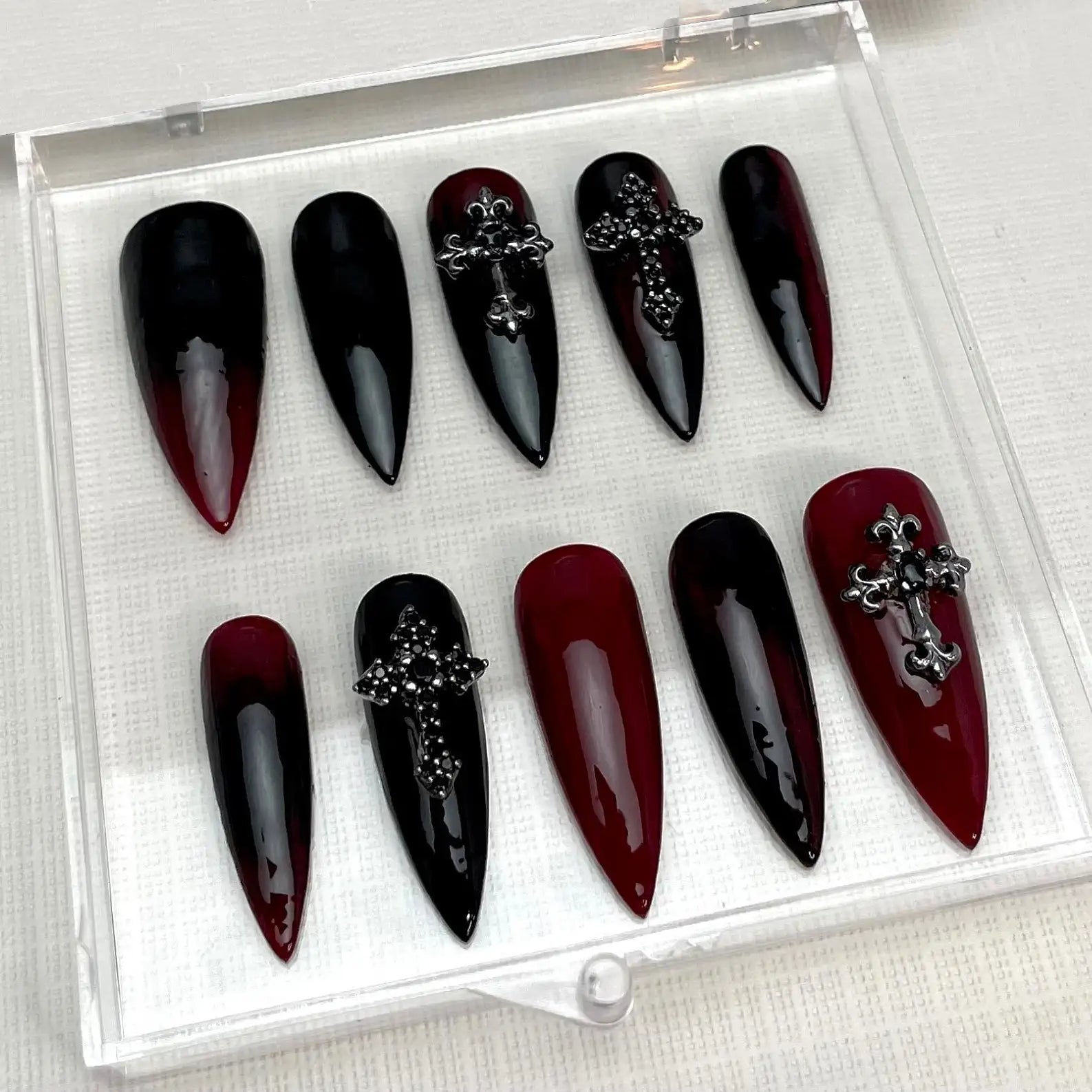 Red and black ombre stiletto Halloween press-on nails with silver cross embellishments.