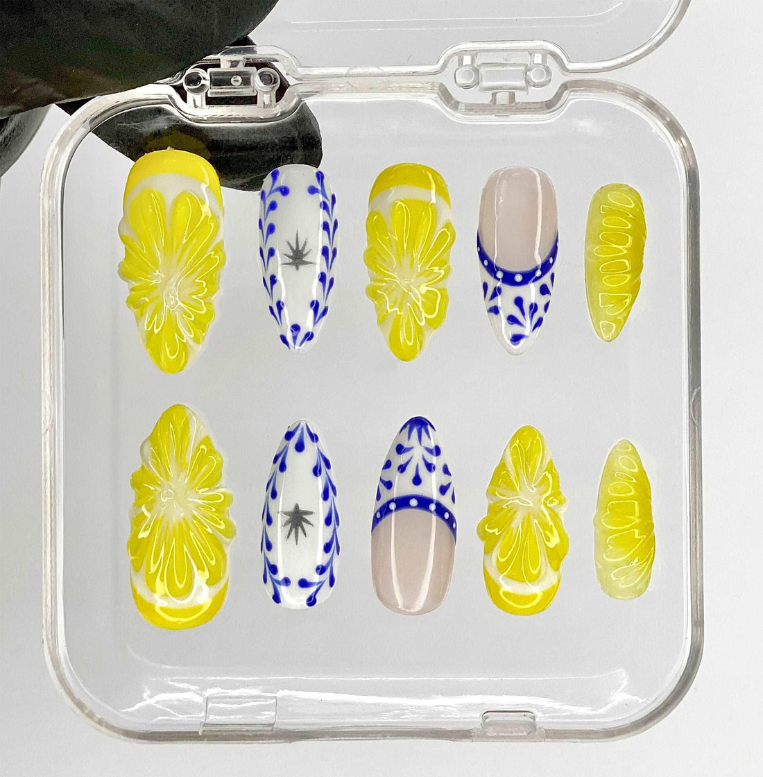 Handmade press-on nails with yellow floral and blue abstract designs in a clear case