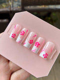Handmade pink floral press-on nails with white tips and pink flower designs
