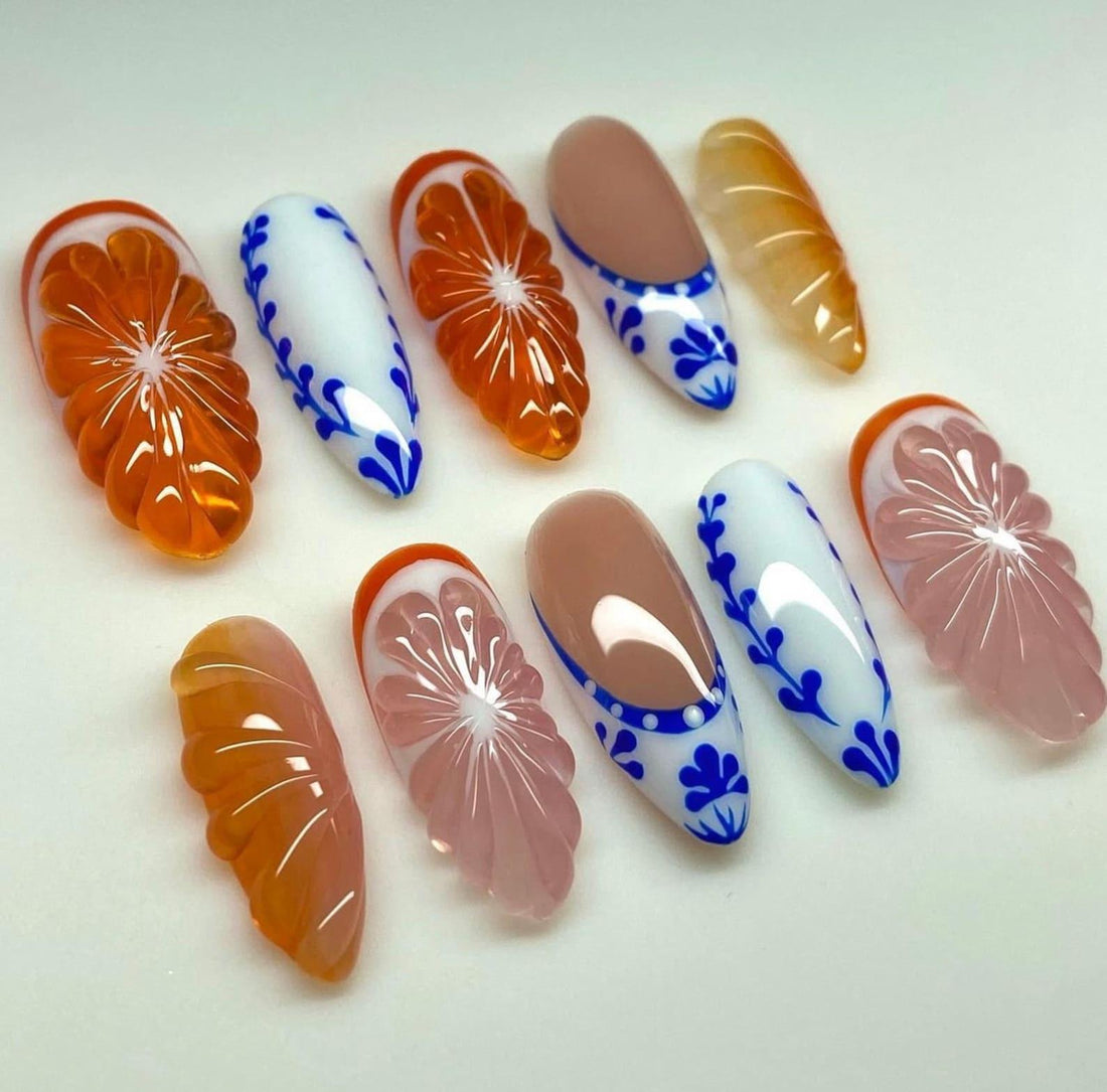 Handmade press-on nails with orange 3D floral, blue and white patterns, and glossy nude accents