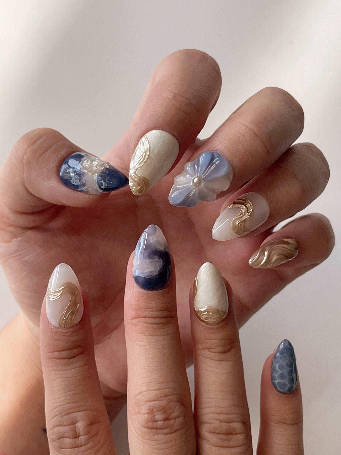 Blue and white handmade press-on nails with gold accents and 3D floral designs