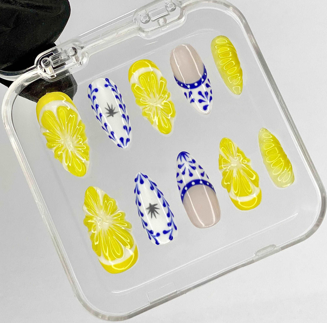 Handmade press-on nails with yellow floral and blue abstract designs in a clear case
