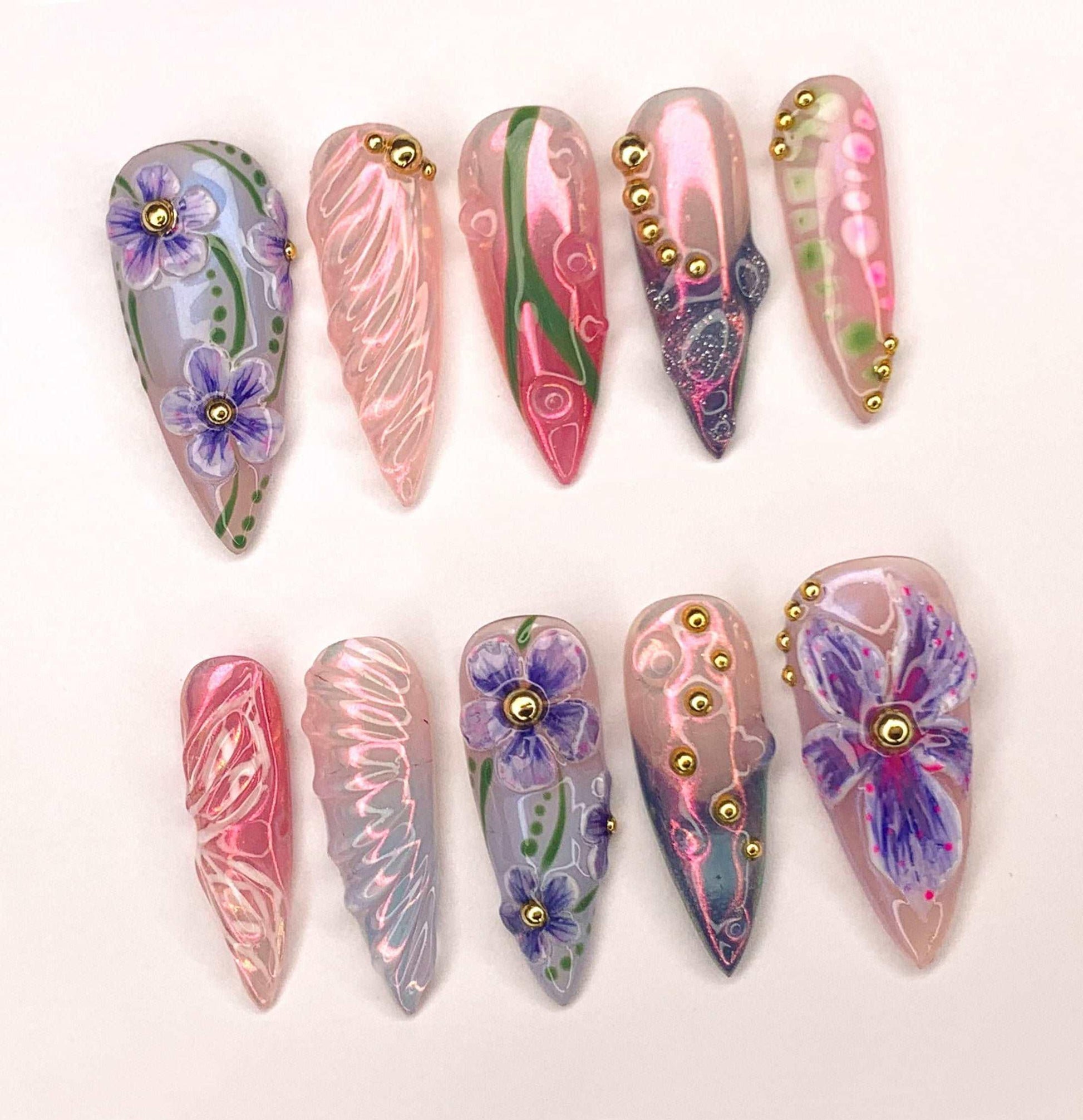 Handmade reusable press-on nails with purple floral designs, gold accents, and pink swirls
