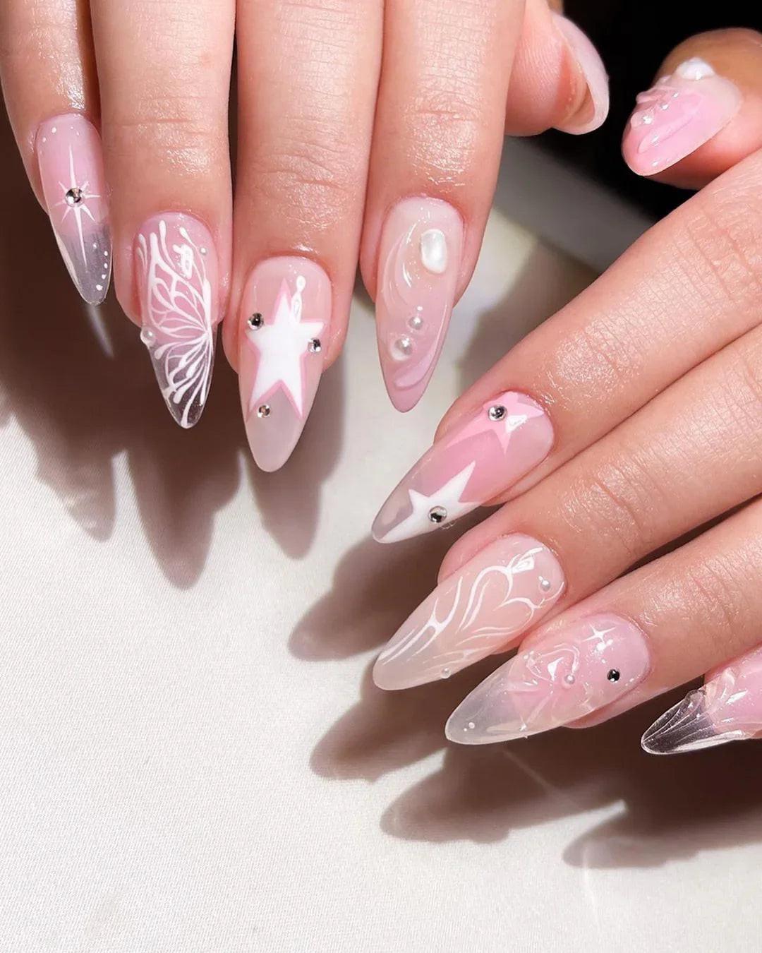 Hand with long stiletto press-on nails featuring pink butterfly, star, and pearl nail art