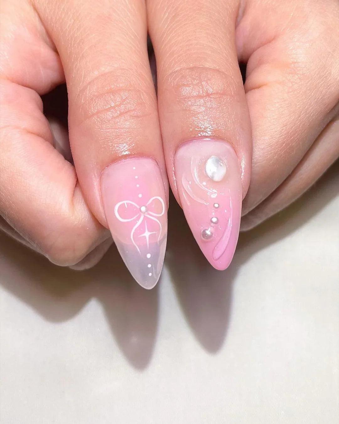 Hand with long stiletto press-on nails featuring pink butterfly, star, and pearl nail art