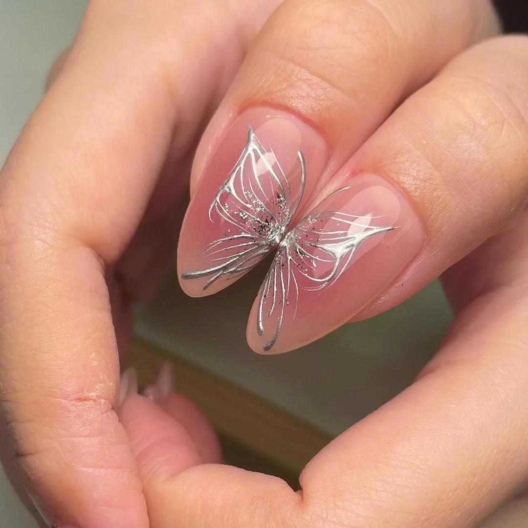 Pink almond-shaped press-on nails with silver star, bow, glitter, and 3D flower accents.