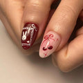 Hand with handmade press-on nails featuring red bunny and cherry nail art designs